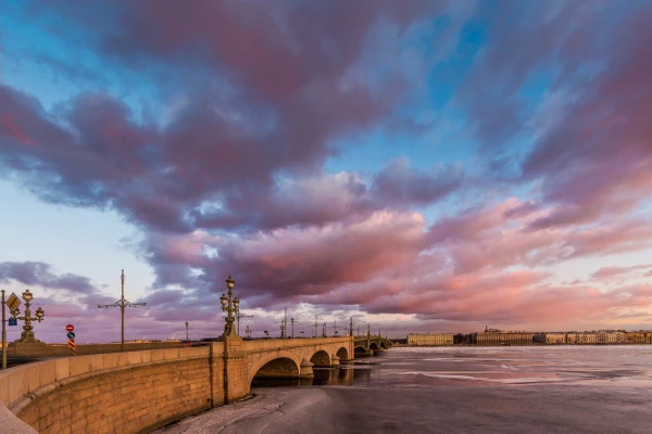 Russia, Saint-Petersburg, 19 March 2016: Pink clouds over the Troitsky Bridge at sunset, drifting ice, frozen Neva River, the traffic on the bridge, a pedestrian walk, Troitskiy