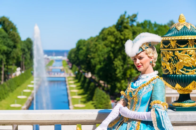 Актриса в старинном костюме встречает туристов в Петродворце в Петергофе